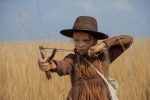 "A young girl draws back on a slingshot and takes aim. "