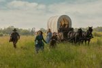 "People run around joyfully with a wagon in the distance. "