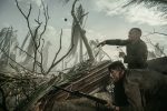 "Two soldiers in muddy uniforms take cover behind debris in a war-torn, smoky battlefield with broken trees, holding rifles and looking alert, surrounded by chaos and destruction."